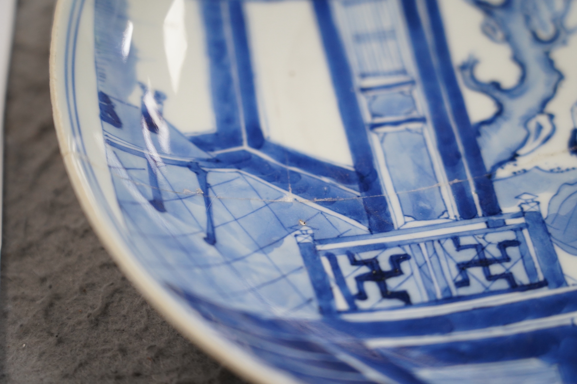 A Chinese blue and white dish, Kangxi period, broken and messily reglued